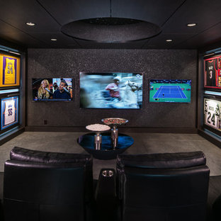 Photo of a traditional enclosed home cinema in Omaha with black walls, concrete flooring, a wall mounted tv and grey floors.