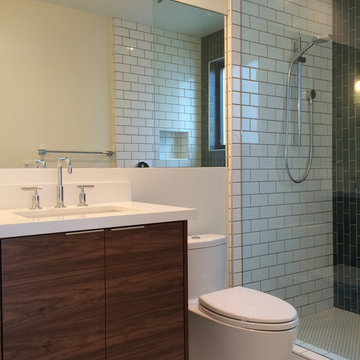 Bath with walnut vanity, recessed mirror, subway tile, and Heath Ceramics blue t