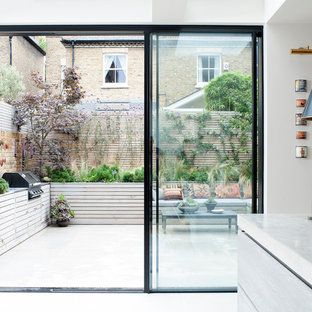 Halbschattiger Stilmix Garten im Sommer, hinter dem Haus mit Kübelpflanzen und Natursteinplatten in London