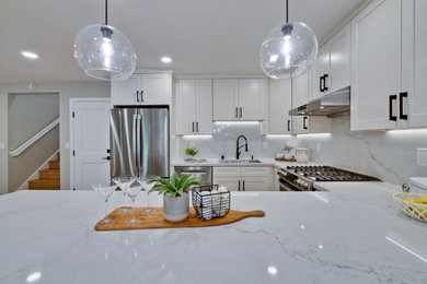 Example of a mid-sized transitional u-shaped laminate floor and beige floor open concept kitchen design in San Francisco with a single-bowl sink, shaker cabinets, white cabinets, quartz countertops, white backsplash, quartz backsplash, stainless steel appliances, no island and white countertops