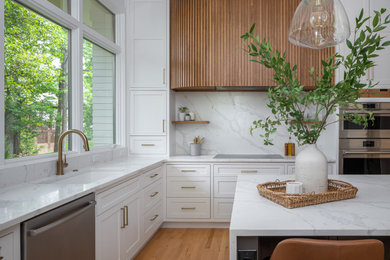 Inspiration for a large transitional u-shaped medium tone wood floor and brown floor enclosed kitchen remodel in Raleigh with an undermount sink, shaker cabinets, white cabinets, quartz countertops, white backsplash, quartz backsplash, stainless steel appliances, an island and white countertops
