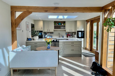 Design ideas for a large rural l-shaped kitchen in Surrey with shaker cabinets, beige cabinets, composite countertops and white worktops.