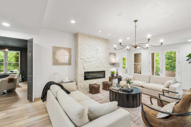 Example of a large transitional formal and open concept light wood floor, beige floor and tray ceiling living room design in Nashville with white walls, a standard fireplace, a stone fireplace and a wall-mounted tv