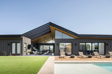 Diseño de fachada de casa gris y negra minimalista de una planta con revestimiento de madera, tejado a dos aguas, tejado de metal y panel y listón