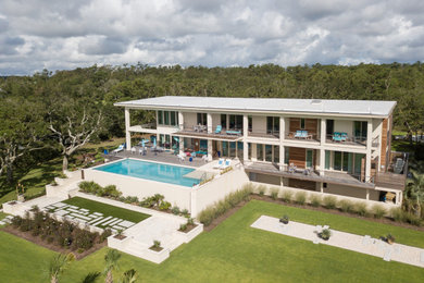 Huge eclectic beige three-story mixed siding and board and batten exterior home photo in Other