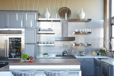 Example of a mid-sized transitional l-shaped dark wood floor and brown floor eat-in kitchen design in Chicago with a farmhouse sink, flat-panel cabinets, gray cabinets, quartz countertops, metallic backsplash, metal backsplash, stainless steel appliances and an island