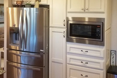 Example of a mid-sized country u-shaped brown floor eat-in kitchen design in Other with a farmhouse sink, shaker cabinets, white cabinets, quartz countertops, white backsplash, ceramic backsplash, stainless steel appliances, no island and brown countertops