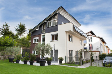 Großes, Dreistöckiges Haus mit Putzfassade, beiger Fassadenfarbe, Pultdach, Ziegeldach, grauem Dach und Verschalung in Stuttgart