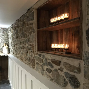 Photo of a medium sized country walk-out basement in Philadelphia with white walls, porcelain flooring, a wood burning stove, a stone fireplace surround and grey floors.