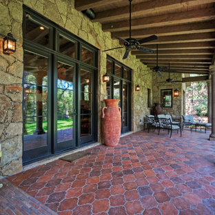 Example of a tuscan patio design in Austin with a roof extension