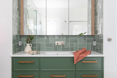 На фото: маленькая главная ванная комната в современном стиле с фасадами в стиле шейкер, зелеными фасадами, отдельно стоящей ванной, душем в нише, унитазом-моноблоком, зеленой плиткой, керамической плиткой, белыми стенами, полом из керамической плитки, врезной раковиной, столешницей из искусственного кварца, бежевым полом, душем с распашными дверями, белой столешницей, нишей, тумбой под одну раковину, встроенной тумбой и деревянным потолком для на участке и в саду с