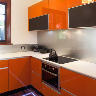 Mid-sized contemporary l-shaped kitchen pantry in Perth with an integrated sink, flat-panel cabinets, orange cabinets, solid surface benchtops, metallic splashback, glass sheet splashback, stainless steel appliances, dark hardwood floors and no island.