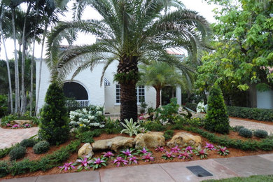 This is an example of a large modern front yard partial sun driveway in Miami with natural stone pavers.