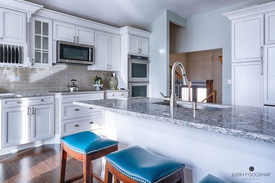 Large elegant dark wood floor eat-in kitchen photo in New York with quartz countertops, stainless steel appliances, an island, white cabinets, an undermount sink, subway tile backsplash and raised-panel cabinets