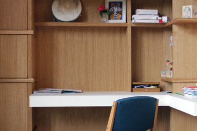 Imagen de despacho actual grande sin chimenea con biblioteca, paredes blancas, suelo de baldosas de terracota, escritorio empotrado y suelo multicolor