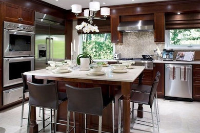 Large modern l-shaped separate kitchen in Las Vegas with shaker cabinets, dark wood cabinets, solid surface benchtops, beige splashback, stainless steel appliances, with island, grey floor and beige benchtop.