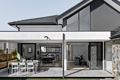 Design ideas for a contemporary two-storey house exterior in Sydney with stone veneer, a tile roof and a grey roof.