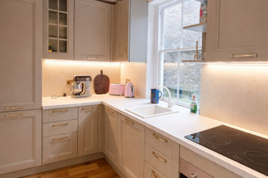 Medium sized modern l-shaped enclosed kitchen with shaker cabinets, beige cabinets, laminate countertops, beige splashback, beige floors and beige worktops.