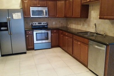 Kitchen - mid-sized traditional l-shaped ceramic tile kitchen idea in Houston with a double-bowl sink, raised-panel cabinets, medium tone wood cabinets, solid surface countertops, beige backsplash, ceramic backsplash and stainless steel appliances