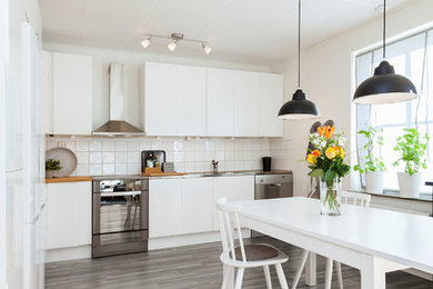 Inspiration for a modern vinyl floor eat-in kitchen remodel in Atlanta with white cabinets, white backsplash, ceramic backsplash and stainless steel appliances
