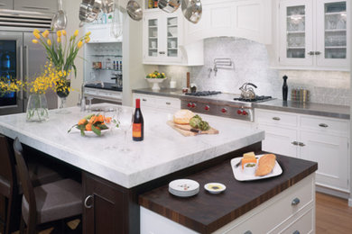 Eat-in kitchen - large traditional l-shaped light wood floor and brown floor eat-in kitchen idea in Seattle with glass-front cabinets, white cabinets, white backsplash, ceramic backsplash, stainless steel appliances, an island and marble countertops