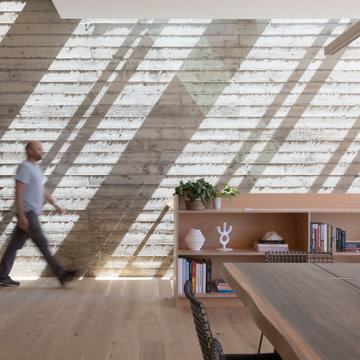Board-formed concrete feature wall with dramatic diagonal skylight shadows