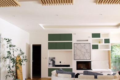 Idées déco pour un grand salon contemporain ouvert avec une bibliothèque ou un coin lecture, un mur blanc, parquet clair, une cheminée d'angle, un manteau de cheminée en plâtre, un téléviseur fixé au mur et un sol marron.