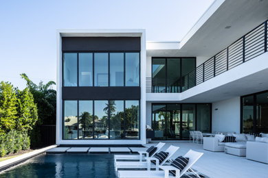 Expansive modern backyard rectangular infinity pool in Miami with a hot tub and concrete pavers.