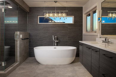 Large modern master bathroom in Omaha with flat-panel cabinets, dark wood cabinets, a freestanding tub, a corner shower, a two-piece toilet, gray tile, porcelain tile, grey walls, porcelain floors, an undermount sink, quartzite benchtops, grey floor, a hinged shower door and white benchtops.