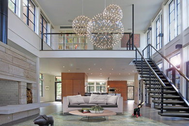Example of a large trendy loft-style medium tone wood floor living room design in New York with white walls, a stone fireplace and a concealed tv