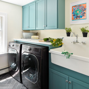 ボストンのトランジショナルスタイルのおしゃれなランドリールーム (エプロンフロントシンク、落し込みパネル扉のキャビネット、ターコイズのキャビネット、ベージュの壁、左右配置の洗濯機・乾燥機、グレーの床、白いキッチンカウンター) の写真