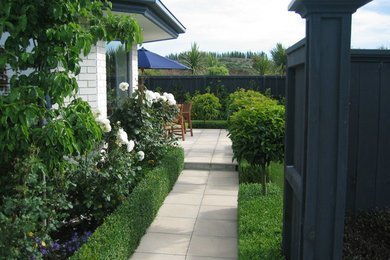 Photo of a mid-sized traditional formal garden in Christchurch with a garden path and natural stone pavers.