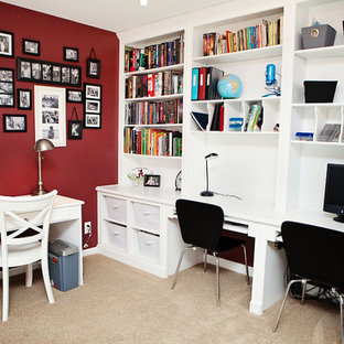 Klassisk inredning av ett mellanstort arbetsrum, med röda väggar, ett inbyggt skrivbord, heltäckningsmatta och brunt golv