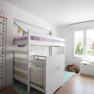 Ejemplo de dormitorio infantil de 1 a 3 años, actual, con paredes blancas, suelo de madera en tonos medios y suelo marrón