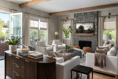 Large transitional open concept medium tone wood floor, exposed beam and wall paneling family room photo in DC Metro with beige walls, a standard fireplace, a stacked stone fireplace and a concealed tv