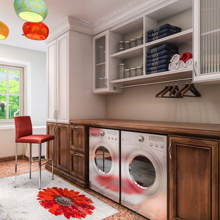 ロサンゼルスの中サイズのトランジショナルスタイルのおしゃれな家事室 (木材カウンター、リノリウムの床、左右配置の洗濯機・乾燥機、オレンジの床、落し込みパネル扉のキャビネット、濃色木目調キャビネット、グレーの壁) の写真