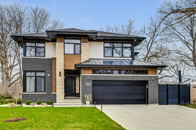 Example of a large trendy black two-story house exterior design in Chicago with a mixed material roof and a black roof