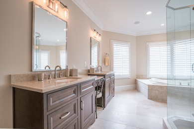 Example of a large classic master beige floor drop-in bathtub design in Atlanta with recessed-panel cabinets, medium tone wood cabinets, beige walls, an undermount sink, a hinged shower door and beige countertops