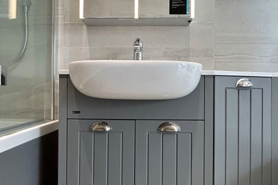 Photo of a small grey and white family bathroom in Hampshire with beaded cabinets, grey cabinets, a built-in bath, a shower/bath combination, a one-piece toilet, grey tiles, porcelain tiles, grey walls, porcelain flooring, a built-in sink, quartz worktops, grey floors, a shower curtain, multi-coloured worktops, a single sink and a built in vanity unit.