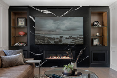 This is an example of a large contemporary family room in Toronto with light hardwood floors, a standard fireplace, a stone fireplace surround and a built-in media wall.