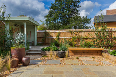 Diseño de jardín campestre pequeño en verano en patio trasero con pérgola, exposición total al sol, adoquines de piedra natural y con madera