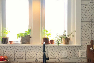 Enclosed kitchen - small transitional l-shaped light wood floor enclosed kitchen idea in Philadelphia with a drop-in sink, recessed-panel cabinets, white cabinets, wood countertops, multicolored backsplash, cement tile backsplash, white appliances, an island and beige countertops