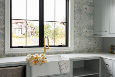Dedicated laundry room - large transitional u-shaped porcelain tile, multicolored floor and wallpaper dedicated laundry room idea in St Louis with a farmhouse sink, flat-panel cabinets, blue cabinets, quartz countertops, blue backsplash, shiplap backsplash, multicolored walls and white countertops