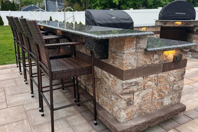 Example of a large trendy backyard concrete paver patio kitchen design in New York with no cover