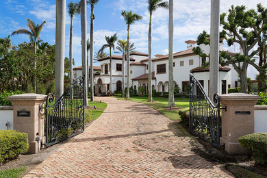 Large traditional beige two-story concrete house exterior idea in Miami with a hip roof and a shingle roof