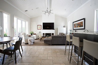 Large trendy open concept travertine floor and beige floor living room photo in Miami with a bar, white walls, a standard fireplace, a plaster fireplace and a wall-mounted tv
