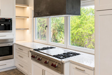 Example of a huge danish u-shaped travertine floor and brown floor eat-in kitchen design in Charleston with shaker cabinets, white cabinets, quartzite countertops, window backsplash, stainless steel appliances, two islands and beige countertops