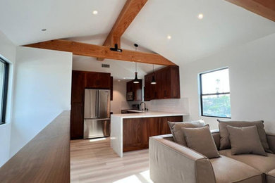 Ejemplo de salón abierto minimalista grande sin chimenea con paredes blancas, suelo de madera clara, suelo marrón y vigas vistas