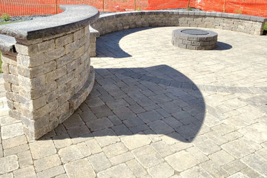 Mid-sized elegant backyard brick patio photo in Other with a fire pit and no cover