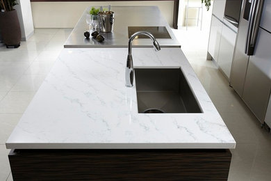Example of a large minimalist galley porcelain tile eat-in kitchen design in Chicago with an undermount sink, flat-panel cabinets, white cabinets, stainless steel appliances and an island